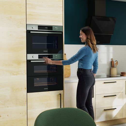 Samsung Series 4 Dual Cook Flex™ Electric Single Oven - Stainless Steel - Woman using control panel of oven in the kitchen