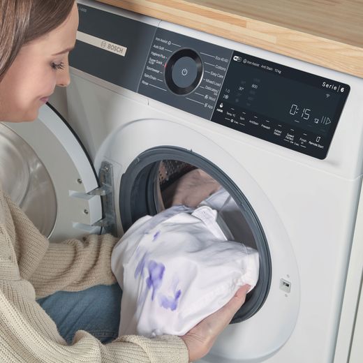 Bosch Series 6 i-Dos WGH254A0GB 10kg WiFi Connected Washing Machine with 1400 rpm - White - person loading machine shot