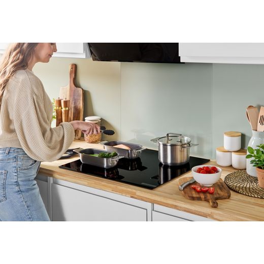 Bosch Series 6 PIX631HC1E 59cm Induction Hob - Black - person cooking on hob shot