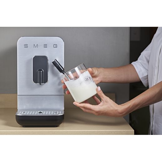 Smeg BCC12BLMUK Coffee Machines Matt Black - Person using machine to get hot coffee shot
