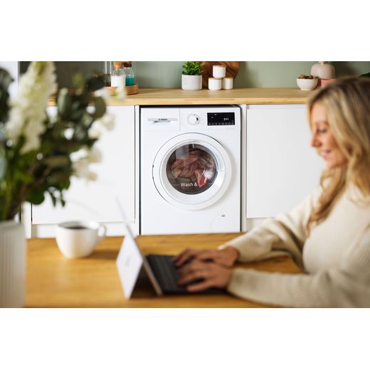 Bosch Series 4 9Kg / 5Kg Washer Dryer - White - Women on table with machine in background shot