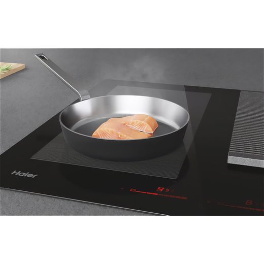 Haier 33803037 83cm Induction Hob - Black - Close up of pan cooking fish on hob shot