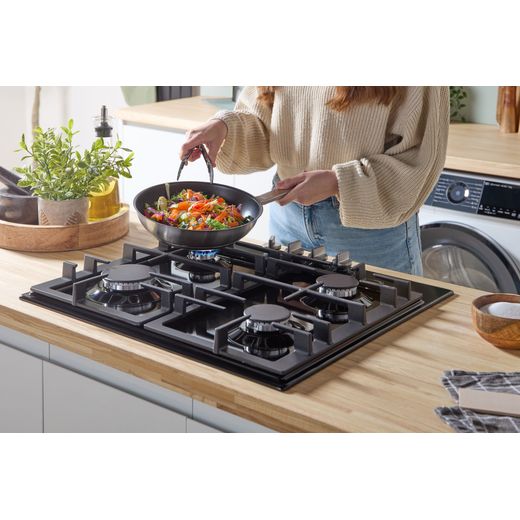 Bosch Series 6 PCP6A6I90 58cm Gas Hob - Black - person cooking on hob shot