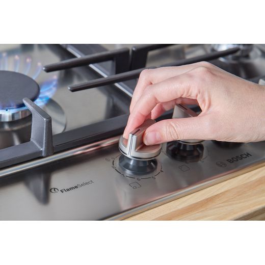 Bosch Series 6 PCP6A5I90 58cm Gas Hob - Stainless Steel - Person turning hob on