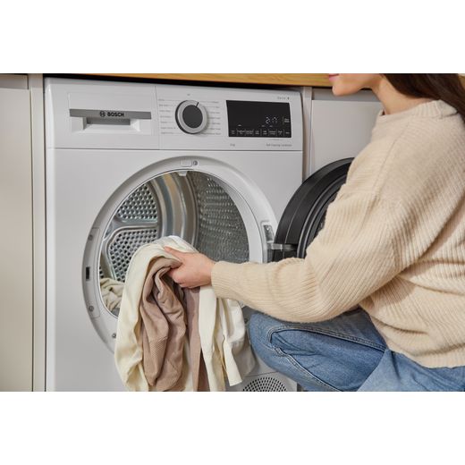 Bosch Series 6 WQG24502GB 9Kg Heat Pump Tumble Dryer - White - person loading drum shot