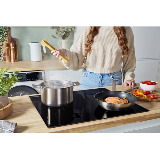 Bosch Series 4 PIE631BB5E 59cm Induction Hob - Black - person cooking on hob shot
