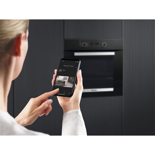 Miele ACTIVE Electric Single Oven - Stainless Steel look - Woman using phone with oven in the background