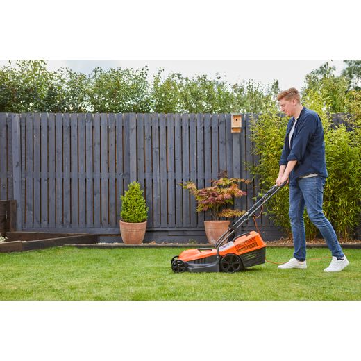 Flymo SimpliMow 320V Corded Lawn Mower - Orange - person cutting grass shot