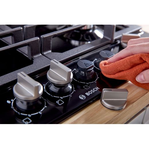 Bosch Series 6 PCP6A6I90 58cm Gas Hob - Black - person cleaning hob