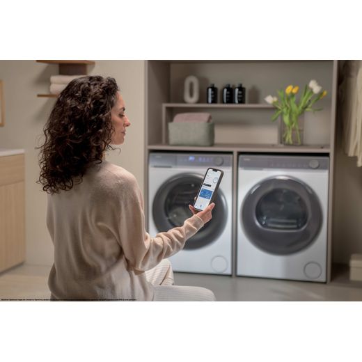 Haier X7 HW120-B14367U-UK 12kg Washing Machine with 1400 rpm - White - Women using phone for washing mahcine