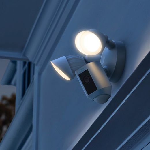 Ring Floodlight Cam Wired Plus Full HD 1080p Smart Home Security Camera - White - Camera at night on wall with lights on shot